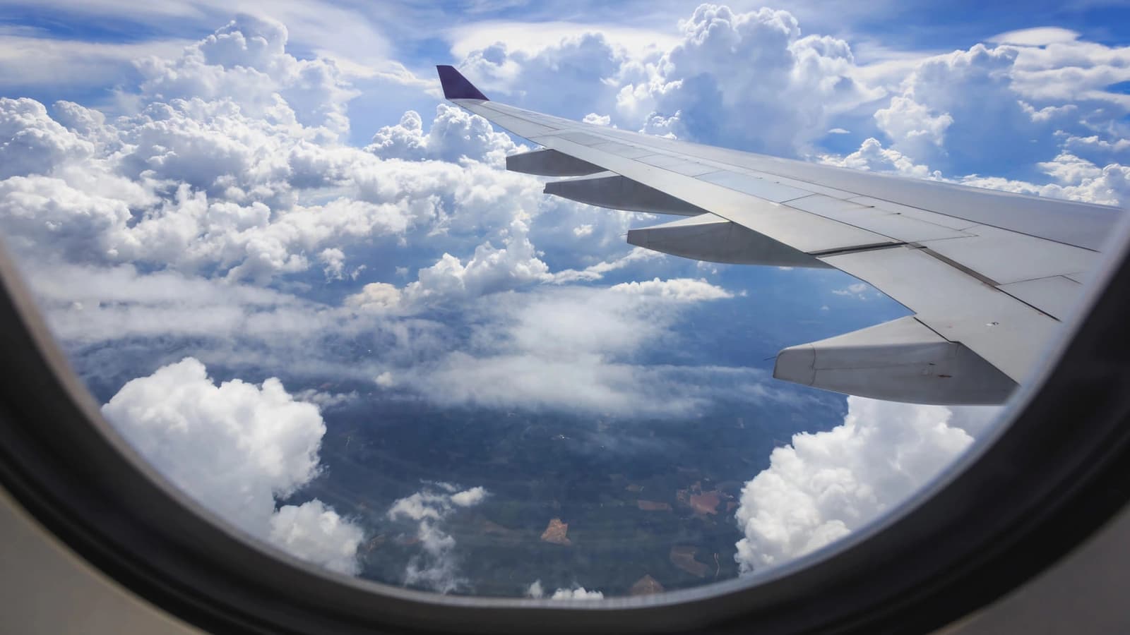 View from an airplane window: wing over bright white clouds